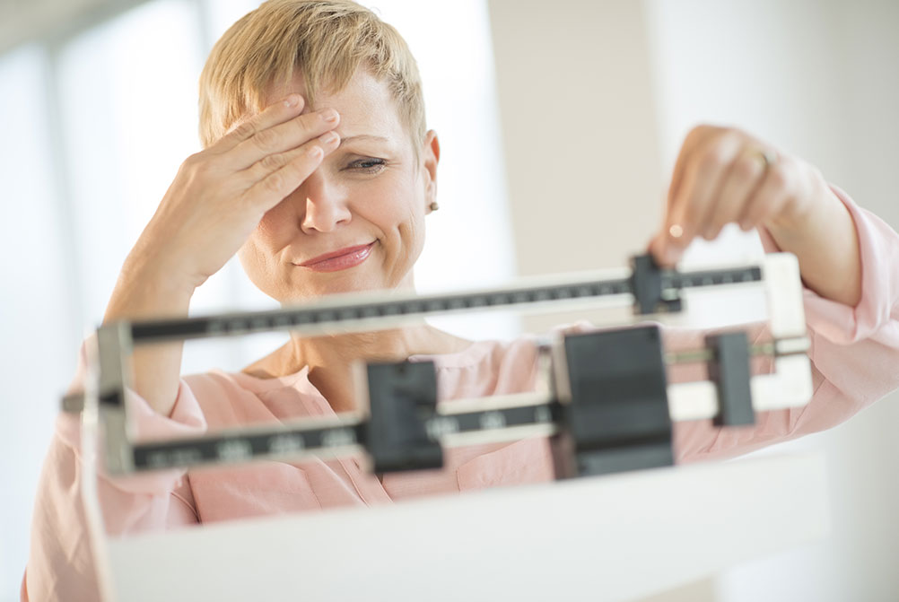 Woman looking apprehensive while weighing herself